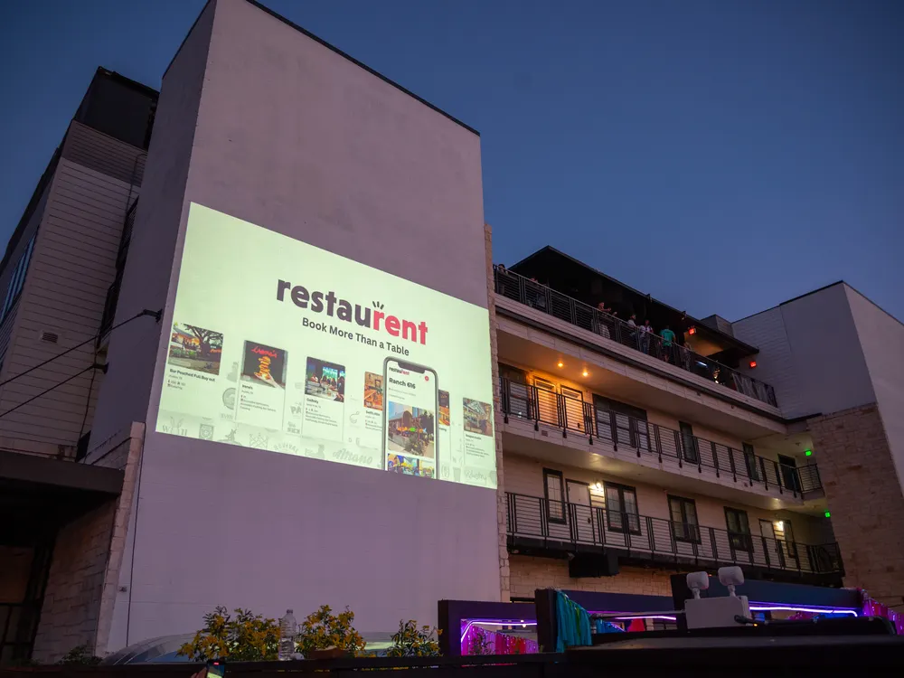 RestauRent logo projected on a building at night