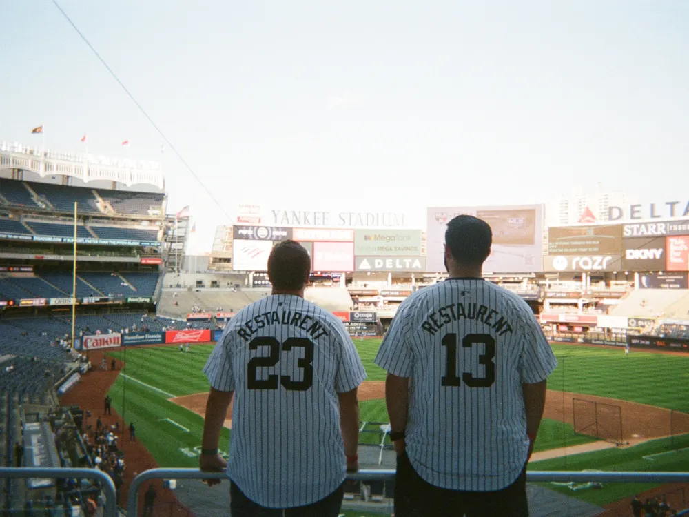 Two teammates in matching jerseys at a baseball stadium